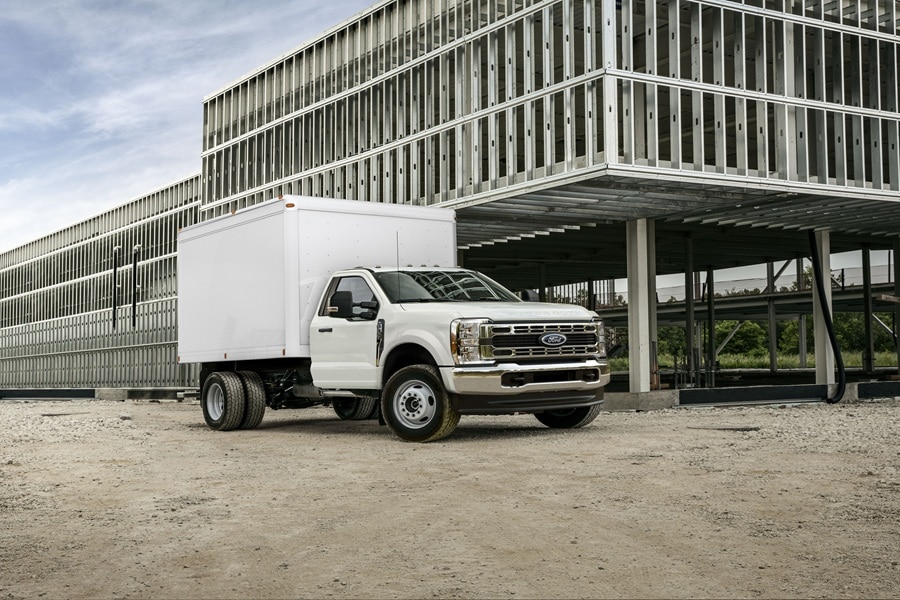 Ford Super Duty Chassis blanca con caja seca estacionada frente a un edificio en construcción.